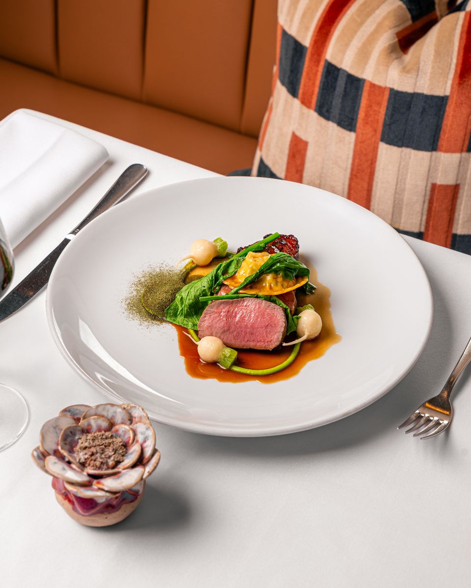 Elegant plated lamb dish on a white plate in a refined restaurant setting